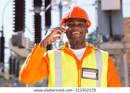happy african electrician using cell phone in electric substation