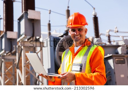 portrait of mid age technical engineer with laptop in power plant