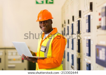 african electrical engineer using laptop computer in power plant control room