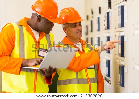 two professional electricians checking industrial control box