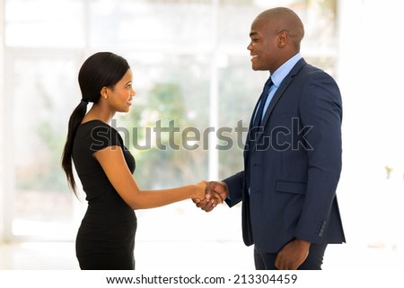 smiling african businessman handshaking with young businesswoman in office