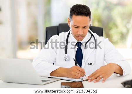 male medical doctor writing reports in his office