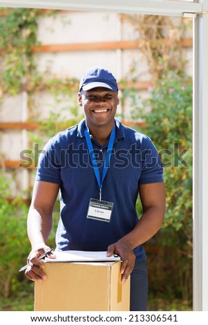 handsome african american delivery man with a parcel standing at the door