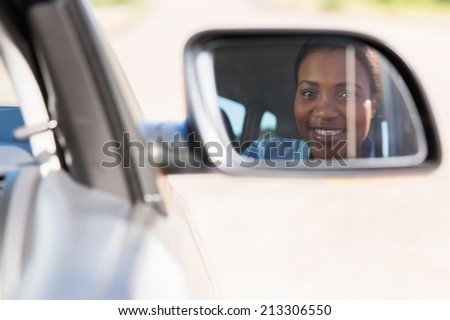beautiful young african female driver looking at side mirror