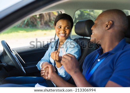 cheerful woman being handed driverÃ?ÃÂ¢??s license by driving instructor in a car