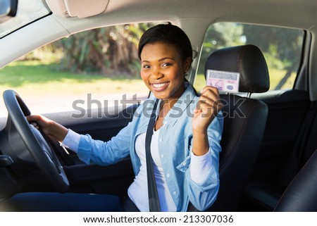 pretty african woman in a car showing her driver\'s license