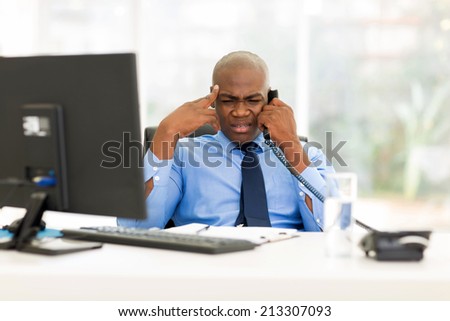confused african business man talking on telephone in office