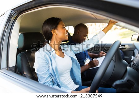 african learner driver adjusting rear view mirror before a driving test