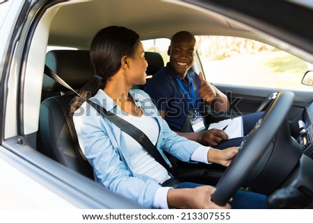 smiling driving instructor giving thumbs up to learner driver during test