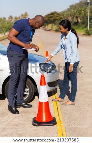 male african instructor marks checklist during a driving test
