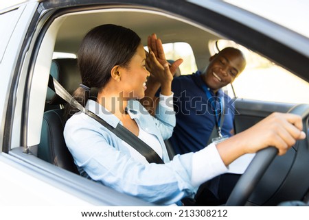 cheerful young african learner driver and driving instructor high five