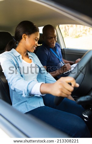 smiling young african girl taking lessons from driving instructor