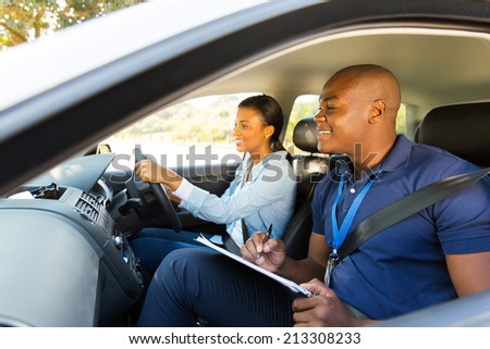 handsome african driving instructor and learner driver inside a car