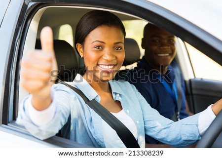 beautiful female african learner driver with instructor giving thumb up
