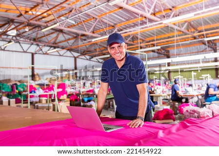 portrait of senior clothing factory manager with laptop computer