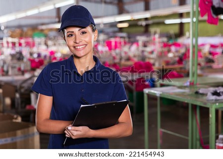 cheerful young clothing factory supervisor standing in production area