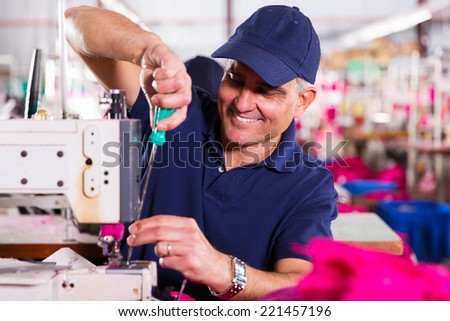 senior mechanic repairing industrial sewing machine in factory