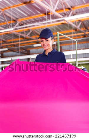 cheerful young textile factory worker holding large pink fabric