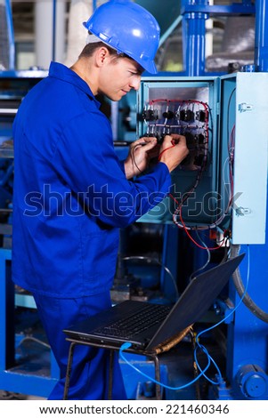 industrial engineer repairing computerized machine with laptop computer