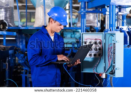 industrial programmer checking control box status with laptop computer