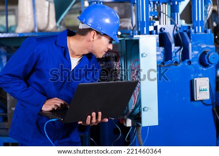 industrial technician checking distribution box with laptop in factory