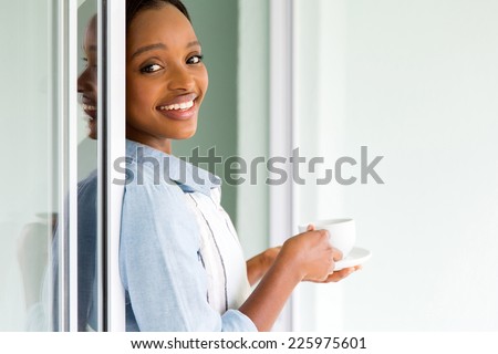 beautiful young african woman drinking tea at home after house chores