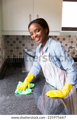 happy young african woman cleaning kitchen counter