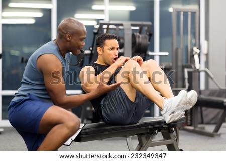 fit middle aged man with personal trainer in gym