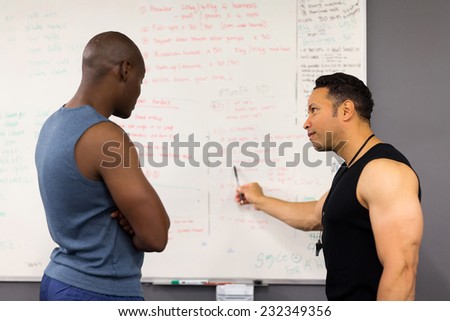 professional personal trainer teaching man in fitness classroom