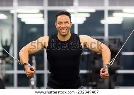 healthy bodybuilder doing triceps pull down practice in gym