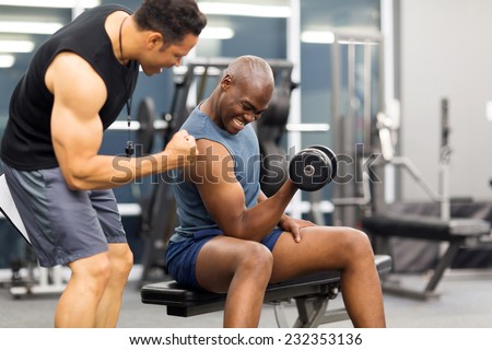 professional gym trainer motivating client to lift dumbbell