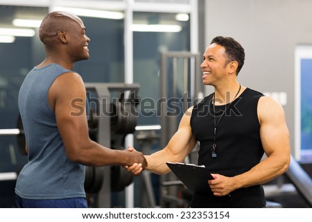 friendly middle aged gym trainer greeting client