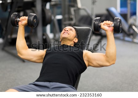 strong middle aged man lifting weights in gym