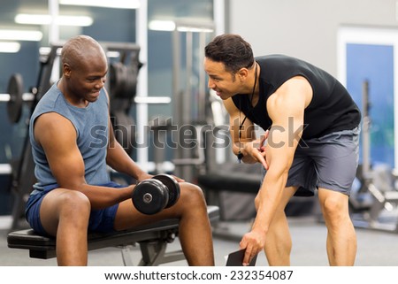middle aged personal trainer training client in gym