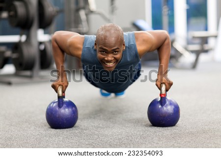 happy young african man doing push-ups exercise with kettle bells