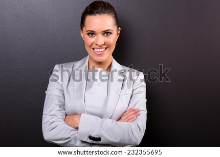 portrait of young business woman with arms folded on black background
