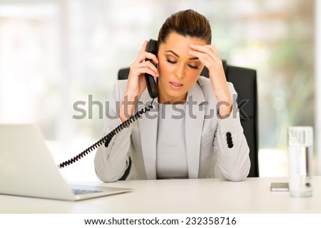 stressed businesswoman talking on telephone in office