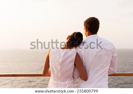 back view of young couple enjoying sunset on cruise