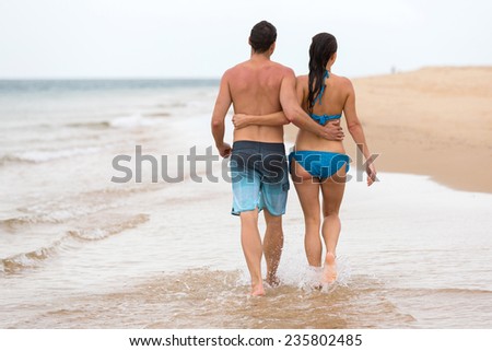 back view of couple walking on beach together