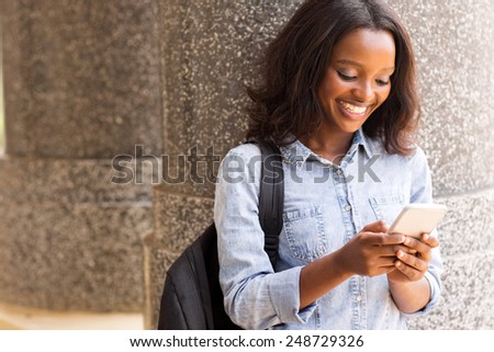 cheerful female afro american university student using cell phone