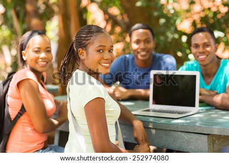 group of african college student relaxing outdoors and looking at the camera
