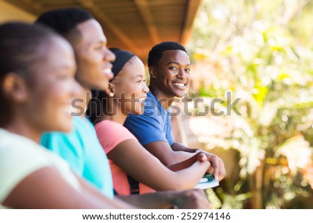 cheerful young african college boy with friends on campus