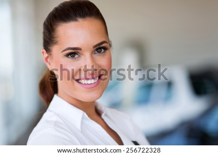 close up portrait of vehicle dealership saleswoman inside showroom