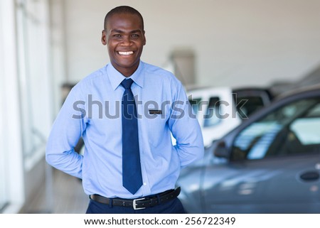 good looking afro american salesman working at vehicle showroom