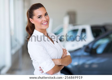 portrait of beautiful vehicle saleswoman with arms folded in showroom