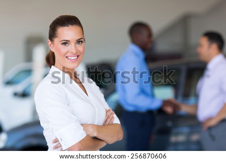 portrait of beautiful young saleswoman standing inside vehicle showroom