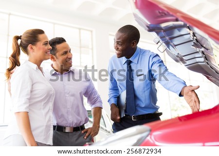 friendly african american vehicle dealer showing couple new car engine