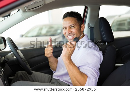 cheerful mid age man giving thumb up inside his new car