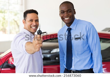 mid age man showing new car key at dealership