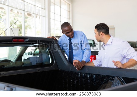 confident car salesman selling a car to middle aged customer